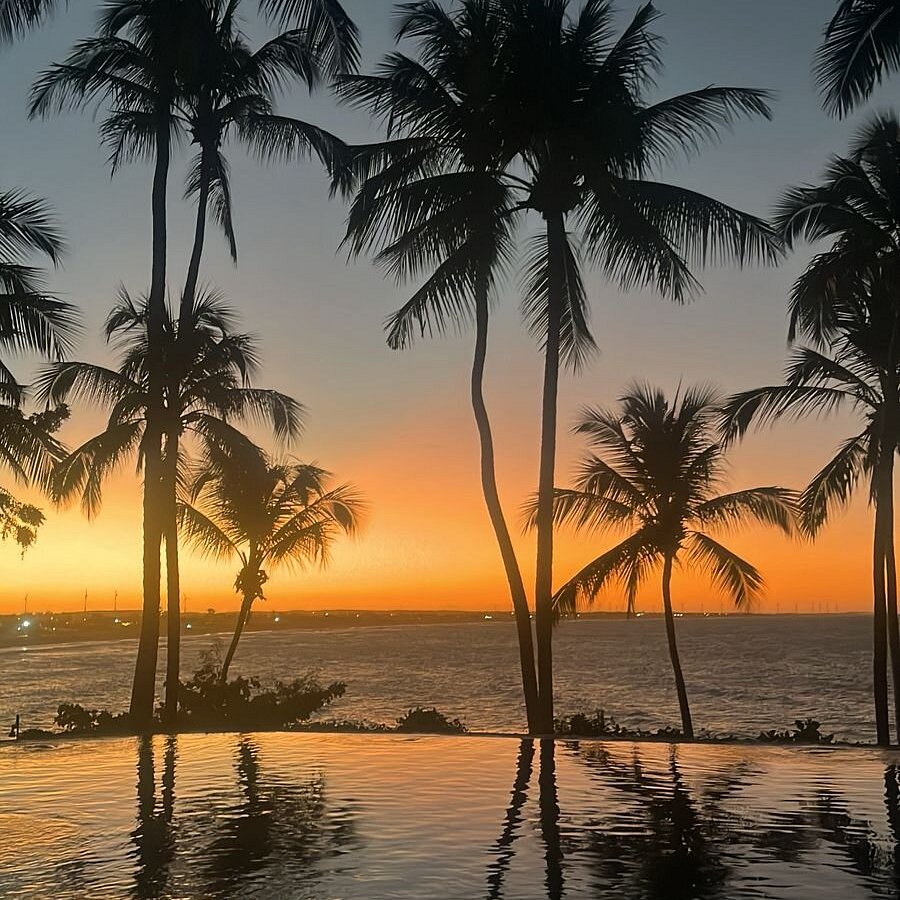 Sunset over palms and infinity pool at Carmel Taíba